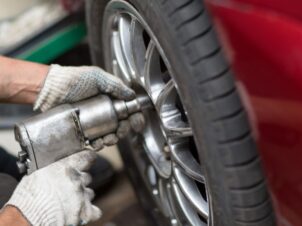 Dekkskift hos Mekonomen, mekaniker skrur til julbolter på rød bil.