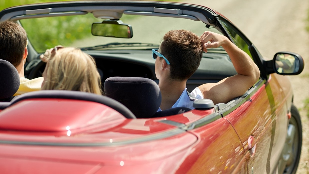 Sommerbilen er klar for sesongen, 3 ungdommer koser seg i en rød cabriolet