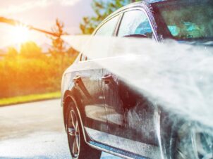 høytrykkspyling av en mørk peronbil i solnedgang