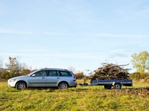 Sølvgrå stasjonsvogn kjører høstløv i tilhengeren